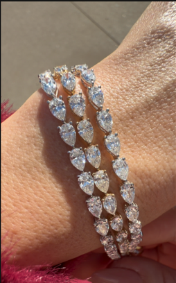Three lab-grown pear-shaped diamond tennis bracelets worn on a wrist, showcasing their brilliant sparkle and elegant design.